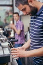 Satisfied barista steaming milk at coffee machine