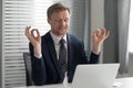 Satisfied businessman relaxing, meditating in yoga pose at workplace Royalty Free Stock Photo