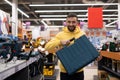 Satisfied buyer of a power tool store holding a case with a smile