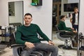 Barber talking to caucasian client man while sitting in chair
