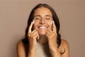 Satisfied caucasian senior lady apply cream on face with closed eyes, enjoy beauty care at home Royalty Free Stock Photo