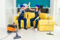 Satisfied cleaners in blue uniforms giving each other high five and continuing to clean the floor in the kitchen.