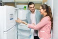 Satisfied couple looking at large fridges