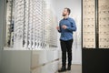 Satisfied Customer. View of happy young male client wearing new glasses, standing near rack and showcase with eyewear Royalty Free Stock Photo