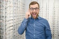 Satisfied Customer. View of happy young male client wearing new glasses, standing near rack and showcase with eyewear Royalty Free Stock Photo