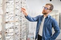 Satisfied Customer. View of happy young male client wearing new glasses, standing near rack and showcase with eyewear Royalty Free Stock Photo