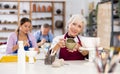 Satisfied elderly woman demonstrates pottery made by own hands