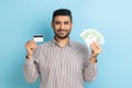 Satisfied excited businessman with beard holding euro banknotes and credit card, looking at camera. Royalty Free Stock Photo