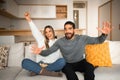 Satisfied excited millennial arab male with beard and european wife watch TV, eat popcorn, enjoy victory