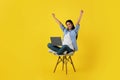 Satisfied excited young korean female sit on chair with laptop, raising her hands, making success gesture Royalty Free Stock Photo