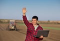 Satisfied farmer with laptop and tractor