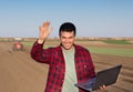 Satisfied farmer with laptop and tractor