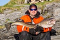 Satisfied fisherman with glasses. holding big fish on his hands. Royalty Free Stock Photo