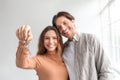Satisfied glad young caucasian couple celebrate buying own apartment at loan, show keys in empty room