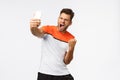Satisfied handsome male athlete in sports t-shirt winning award, sharing great news, achievement social media followers Royalty Free Stock Photo