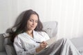 Satisfied and happy smiling girl lying on the bed in the room and writes a journal of your dreams, plans, goals, experiences, idea Royalty Free Stock Photo