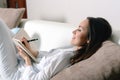 Satisfied and happy smiling girl lying on the sofa in the room and writes a journal of your dreams, plans, goals, experiences, ide Royalty Free Stock Photo