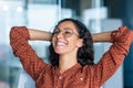 Satisfied happy and successful business woman smiling and resting, hispanic female worker finished work and put her Royalty Free Stock Photo