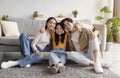 Satisfied happy young asian mother, father and teen daughter hugs, sits on floor in living room interior Royalty Free Stock Photo