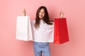 Satisfied little girl holding shopping paper bags, excited with mall discounts, good purchases.