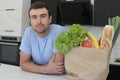 Satisfied looking man with groceries over kitchen counter Royalty Free Stock Photo