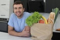 Satisfied looking man with groceries over kitchen counter Royalty Free Stock Photo