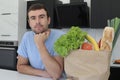 Satisfied looking man with groceries over kitchen counter Royalty Free Stock Photo