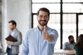 Satisfied loyal male client posing in office raising thumb up