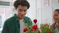 Satisfied man smell flowers in shop. Happy african guy buy bouquet in store.