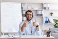 Satisfied mature european male in glasses and headphones showing thumbs up sign in living room