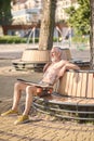 Satisfied mature man with longboard sitting on the bench.