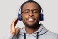 Satisfied millennial african american man wearing modern wireless earphones.