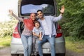 Satisfied millennial arab husband, wife in hijab and small boy waving hands sitting in car trunk Royalty Free Stock Photo