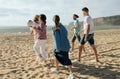 Satisfied millennial arabic and caucasian people in casual with balls have fun, go to play active game on beach Royalty Free Stock Photo