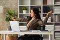Satisfied millennial businesswoman relaxing in office chair and stretching her arms Royalty Free Stock Photo