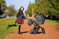 Satisfied mom on a walk with a stroller. Young mother walking with baby in the park. Beautiful smile and uplifted mood, satisfied