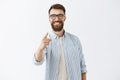 Satisfied and pleased handsome male entrepreneur feeling delighted with good work of employee pointing with index finger