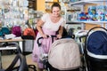 satisfied pregnant woman looking for baby carriage at kids shop