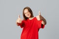 Satisfied pretty brunette teen girl in casual red t shirt looking happy, thumbs-up in approval, like and agree, support friends Royalty Free Stock Photo