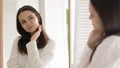 Satisfied pretty young woman looking at mirror in bathroom