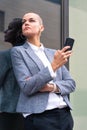 Vertical portrait caucasian business woman using an app on her smartphone outdoors. Royalty Free Stock Photo