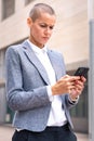 Vertical portrait caucasian business woman using an app on her smartphone outdoors. Royalty Free Stock Photo