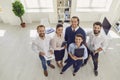 Satisfied Sales Department employees standing in company office looking at camera