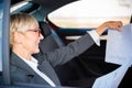 Satisfied senior manager or businesswoman looking at sales report charts while riding on a back seat of the car Royalty Free Stock Photo