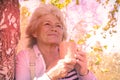 Satisfied senior woman breathing fresh air holding a coffee cup standing outdoors in the park Royalty Free Stock Photo