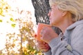 Satisfied senior woman breathing fresh air holding a coffee cup standing outdoors in the park Royalty Free Stock Photo