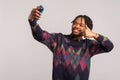 Satisfied smiling african man with dreadlocks and beard showing thumbs up looking at camera of mobile phone, video call, Royalty Free Stock Photo