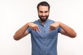 Satisfied successful man with beard pointing fingers down paying attention at advertising area, showing freespace, looking at Royalty Free Stock Photo