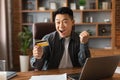 Satisfied surprised excited adult japanese businessman with open mouth hold credit card, make win gesture