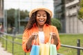 Satisfied surprised millennial african american lady in casual and hat opens bags, enjoys purchases, gift and surprise Royalty Free Stock Photo